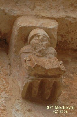 IGLESIA DE SAN MIGUEL DE SAN ESTEBAN DE GORMAZ (SAN ESTEBAN DE GORMAZ, SORIA) | CANECILLO CON PERSONAJE RELIGIOSO QUE SOSTIENE UN LIBRO ABIERTO CON LA FECHA DE CONSTRUCCIÓN DE LA IGLESIA | © ART MEDIEVAL 2006
